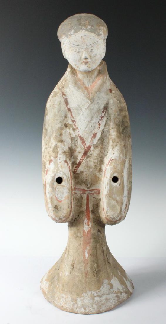 A LARGE CHINESE HAN POTTERY FIGURE: Han Dynasty (206 BC - 220 AD) Figure of a Standing Courtesan, with original separate head, lacking hands, her body slightly stooped in an offering stance, decorated with remnants of tan, red, white an