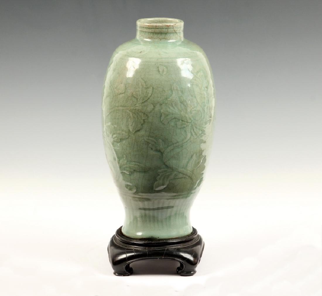 CHINESE CELADON VASE: Chinese Ming Dynasty Period Celadon Glazed Porcelain Vase, with carved floral decoration to body, ribbed texture around base, incised neck and shoulder bands, craquelure surface, with carved wooden st