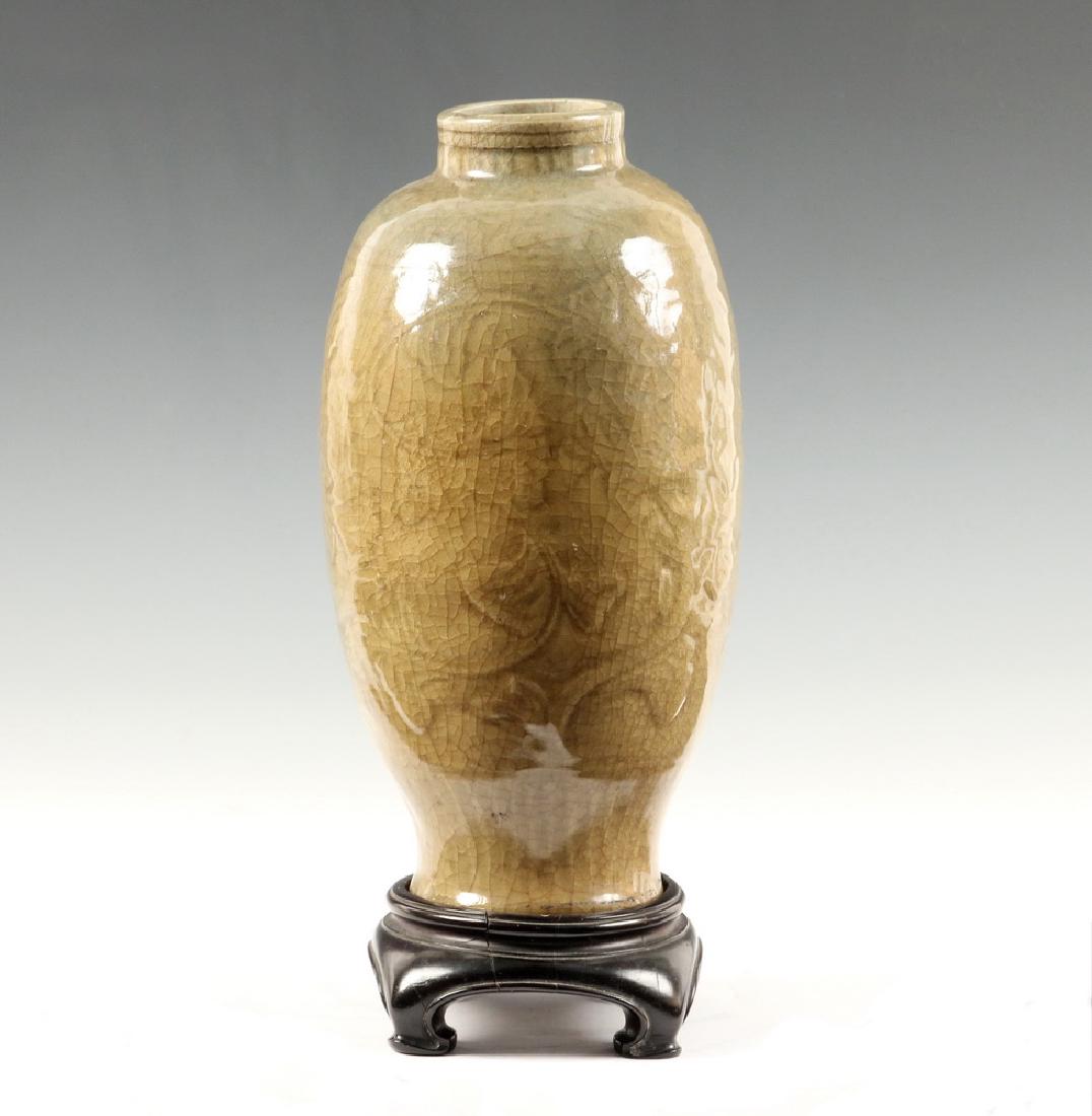 CHINESE CELADON VASE: Chinese Ming Dynasty Period Dark Celadon Glazed Porcelain Vase, with carved floral decoration to body, ribbed decoration to neck and around base, craquelure surface, glazed foot, on carved wooden stan