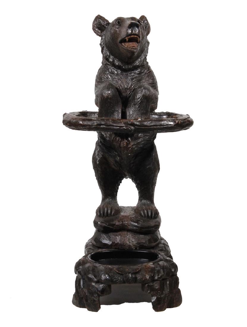 GERMAN BLACK FOREST CARVED BEAR UMBRELLA/CANE STAND: 19th c. Carved Walnut Umbrella Stand consisting of a bear with glass eyes, with open mouth, rearing up on hind legs, holding a branch-form ring, on a natural form footed plinth with oval black painted