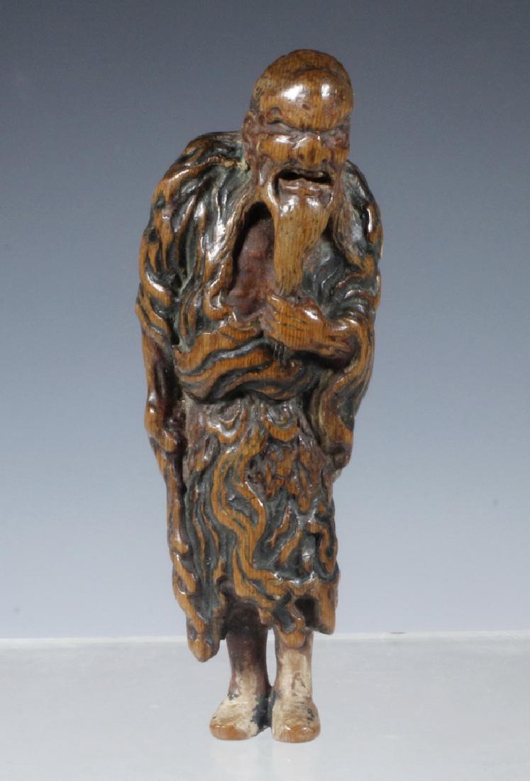 18TH C CARVED WOOD JAPANESE NETSUKE OF MAN W/ CLUB: Edo period carved boxwood figure of a standing Ascetic Elderly Traveler, with remnants of paint, 3 5/8" tall. Worn from years of use, nice patina. Provenance: From the estate of Nancy Hamilton.