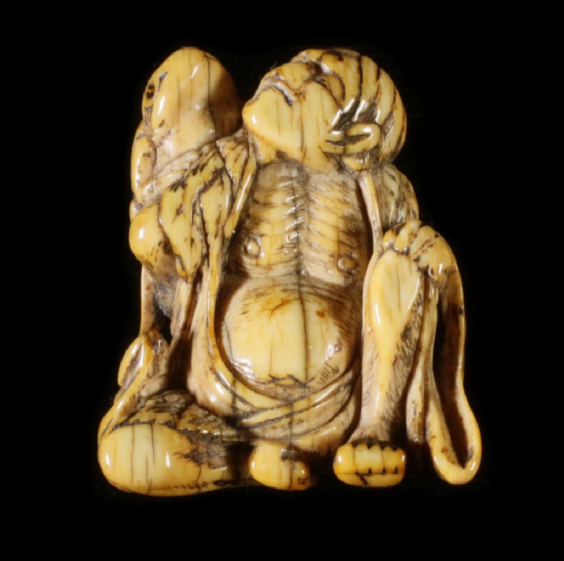 18TH C. CARVED NETSUKE OF AN OLD MAN SEATED WITH FROG: Edo Period figure of an ascetic monk with a large frog on his shoulder, both have their eyes raised to the sky, the man's ribs showing through his tattered robe, his right hand behind his back graspin