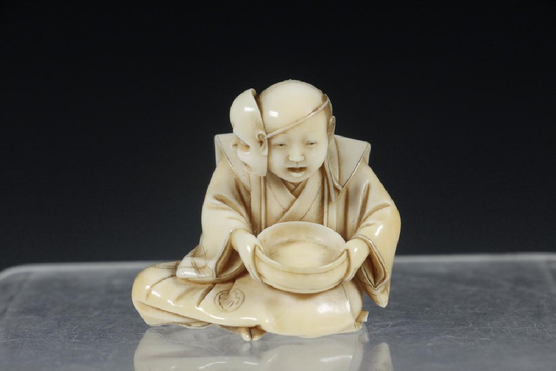 19TH C. JAPANESE CARVED NETSUKE OF A SEATED ACTOR WITH: Meiji Period Netsuke of a Seated Noh Theatre Trainee, with mask pushed to one side of his head, holding an inverted drum in his lap, having a cinnabar block signature on the finished underside, clan m