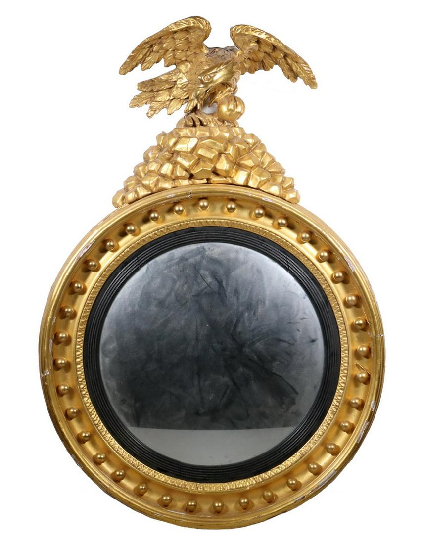 FEDERAL PERIOD BULL'S-EYE MIRROR: Fully Gilt Frame with convex glass, cove surround having polished gilt spheres, reeded ebony liner, surmounted by a spreadwing expressive eagle atop a revetment of boulders, 14 1/2" glass, 22" x 23" o