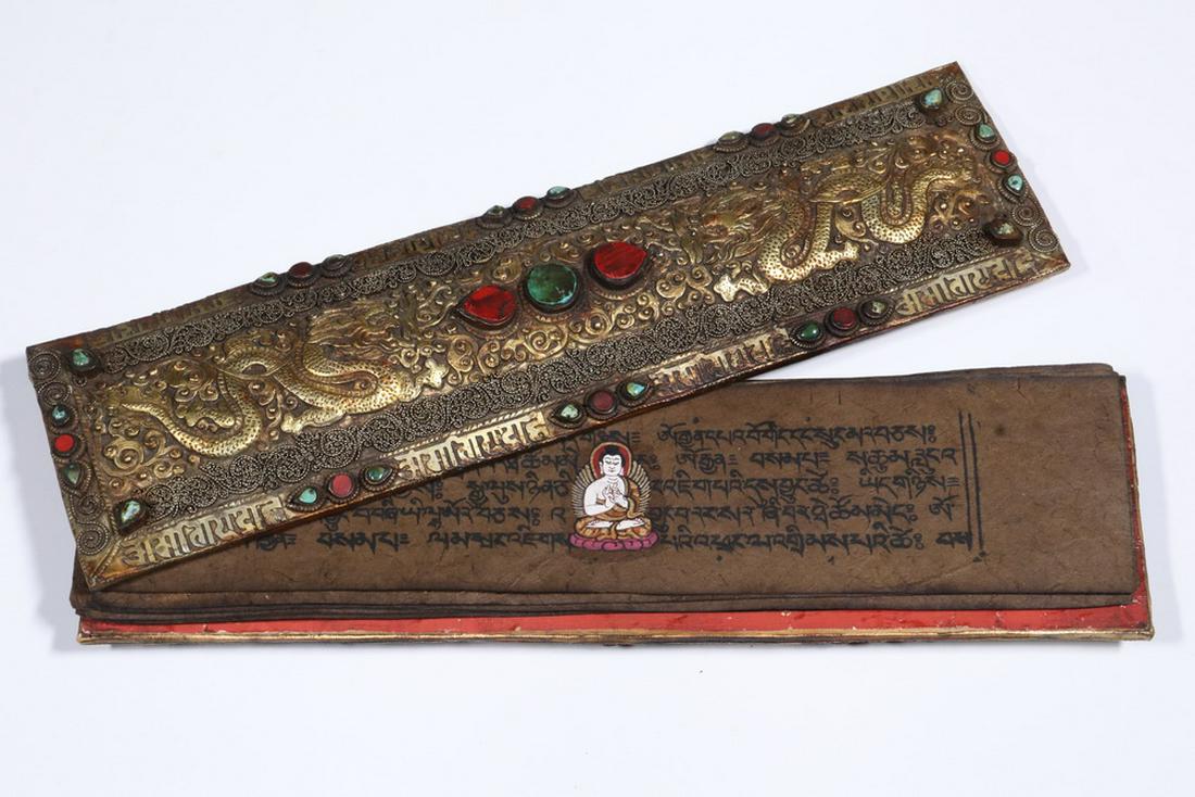 REPOUSSE GILT METAL TIBETAN PRAYER BOX: Late 19th - Early 20th c. Tibetan or Bhutanese Prayer Box, repousse with gilt dragons and filigree work, ornamented with inserts of coral and turquoise, inside are pages from an illuminated text, 14" 