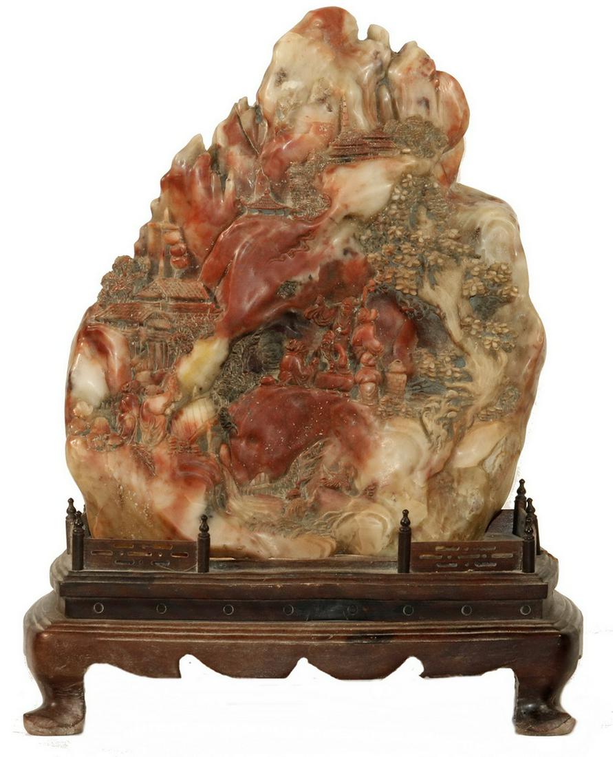 SCHOLAR'S STONE ON STAND: Chinese Carved Scholar's Stone on Stand, relief carved soapstone depicting a mountainous scene with figures, building and trees, set on a carved wooden stand with gallery, 15" high, 11" x 6 1/4". Crac