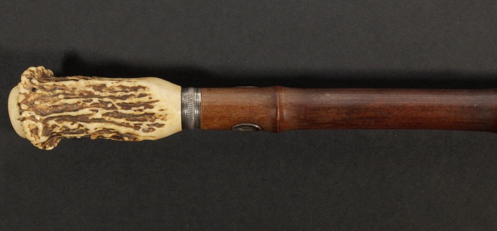 LADY'S WALKING STICK: Bamboo Walking Stick with Horn Handle, silver band, inset top plaque, and handle escutcheons, metal base tip, 34 5/8" long, 1" diam. at top. Base tip dents.