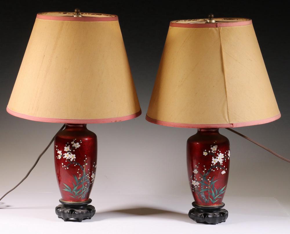PR JAPANESE RED CLOISONNE TABLE LAMPS: Pair of Vintage Japanese Pigeon Blood Red Cloisonne Vases, as table lamps (not drilled), each with floral and bamboo decoration, set on carved wooden bases, with harps, finials, and paperboard shades,