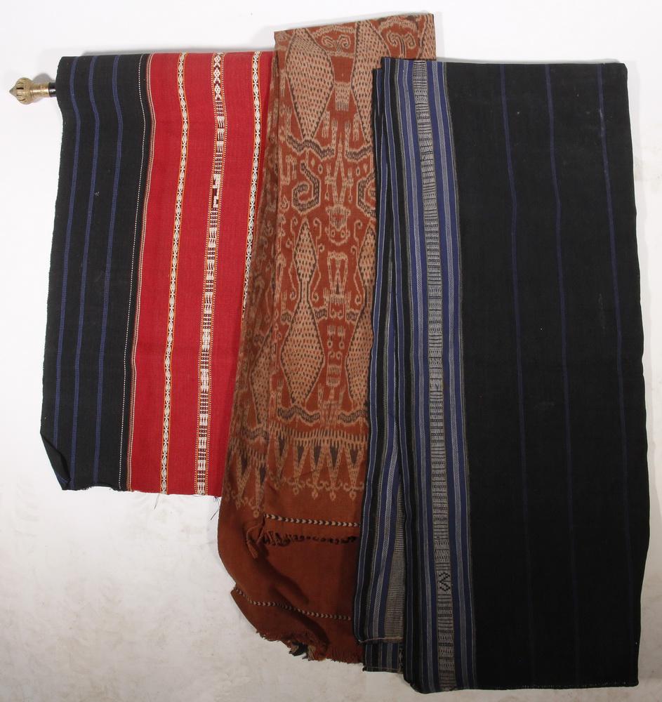 (6) INDONESIAN TEXTILES, FOUR WITH HANGERS: Group of (6) Indonesian Crafted Textiles, including: Woven and embroidered runner in purple, rose, burgundy, orange and blue, with fringed ends, and carved wooden hanger, runner: 24 3/4" x 91" w/o fri