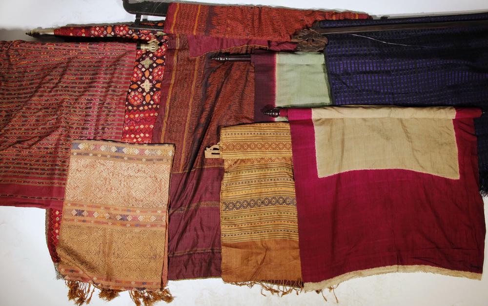 (8) INDONESIAN TEXTILES, SEVEN WITH HANGERS: Group of (8) Indonesian Assorted Textile Panels, (7) with carved wooden hangers, including: Burgundy and green silk panel, 30 1/2" x 61 3/4", with hanger: 40 1/4" wide, holes and stains; Burgundy and 