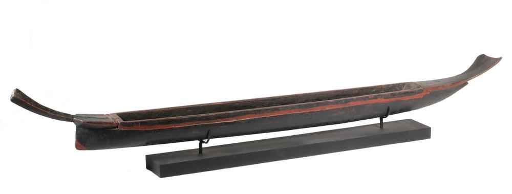 INDONESIAN MODEL OF A DUGOUT CANOE: Carved of one piece, in black and red paint, having a fishtail stern, displayed on stand, 33 1/2" long, chip to tail. WWII vintage.