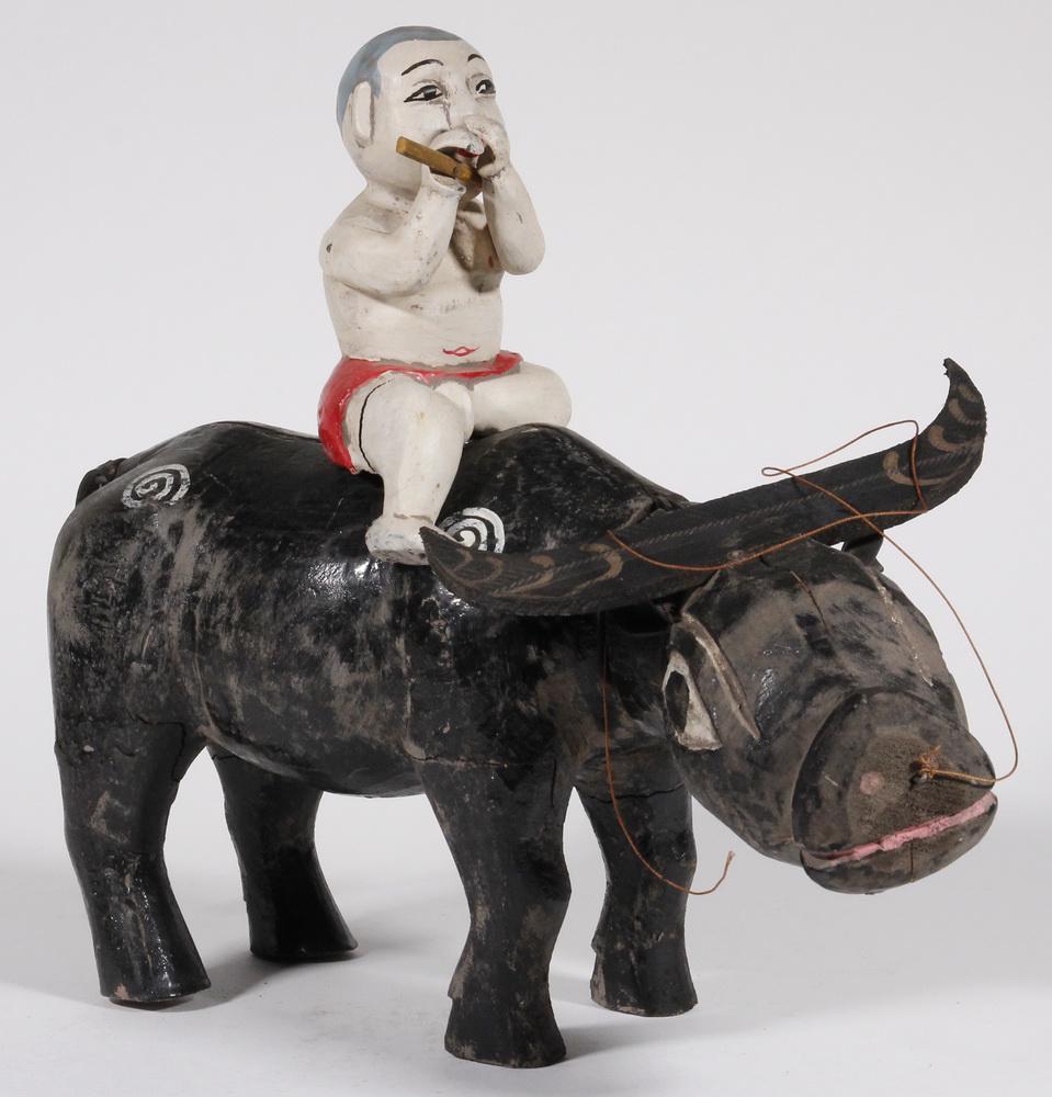 VIETNAMESE CARVED WATER PUPPET: Carved and Painted Vietnamese Articulated Puppet, depicting a boy flute player atop a water buffalo, 13 1/2" high, 16" x 5". Paint losses and surface wear, crack in boy's right leg.