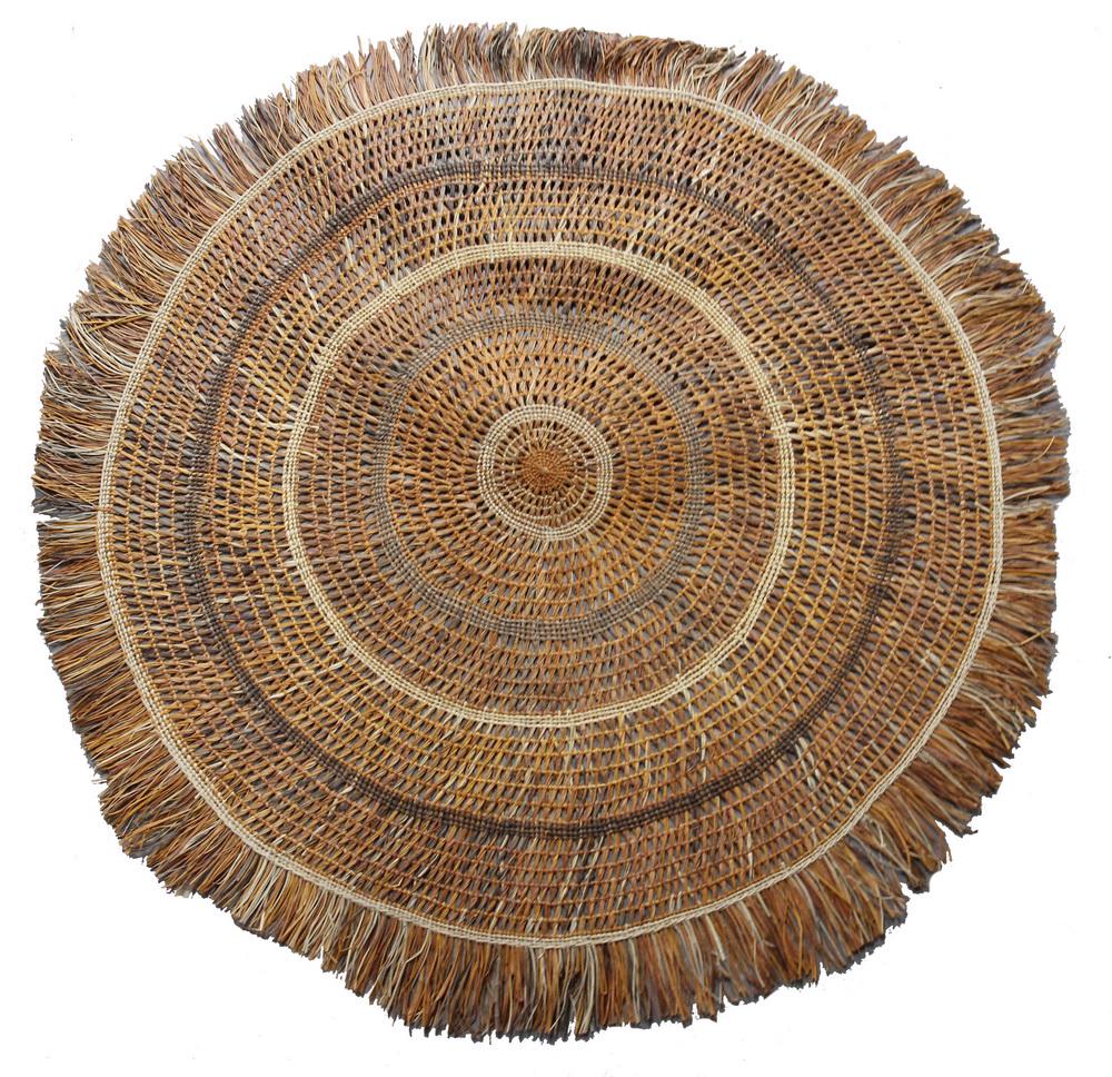 ROUND WOVEN REED FLOOR COVERING, MALAYSIA-SARAWK: Sunburst Floor Mat in shades of orange and brown, 60" diam., including the 5" fringe. Very good condition.