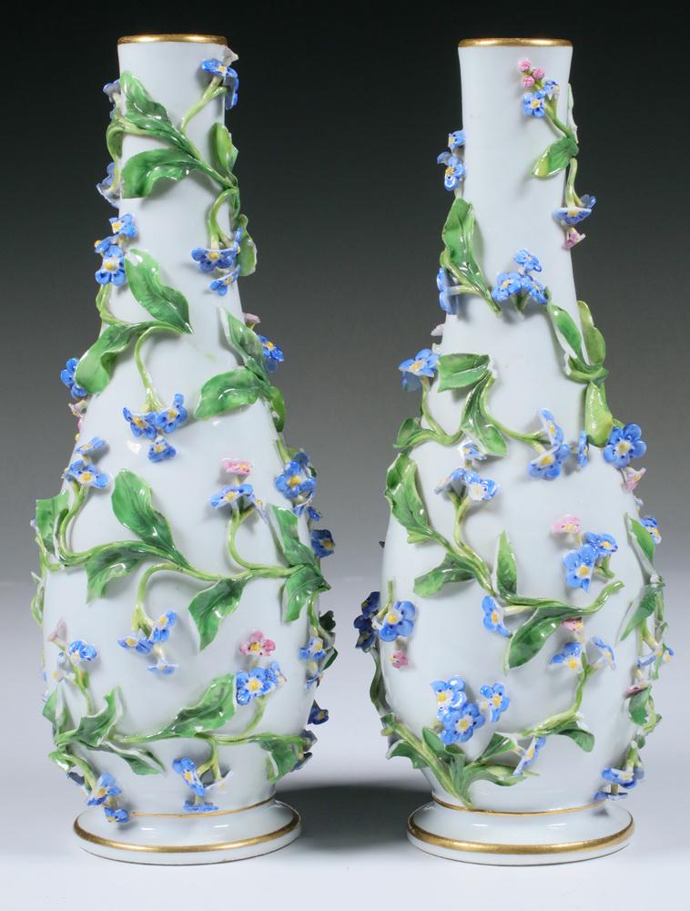 PR MEISSEN PORCELAIN VASES: Pair of Meissen German Porcelain Bottle Form Vases, late 19th - early 20th c., with raised floral and vine covered surfaces, gilded rims, blue crossed swords with curved handles mark, base also impres
