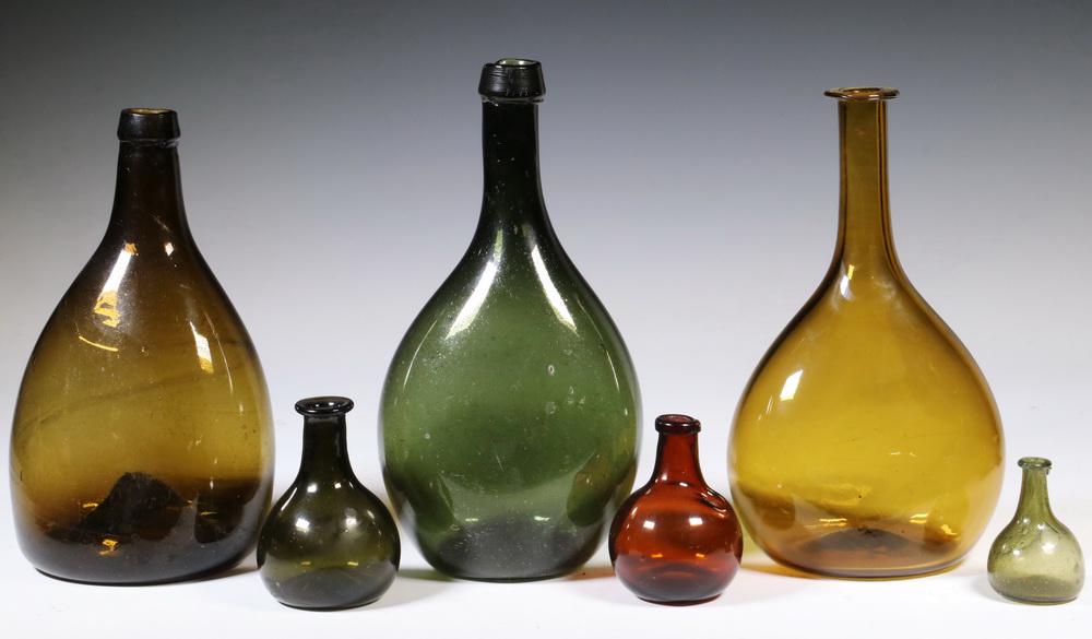 (6) EARLY AMERICAN BLOWN GLASS CHESTNUT FLASKS: Group of (6) Late 18th - Early 19th c. Free Blown New England Chestnut Bottles, in amber and olive green, including: Large olive green flask with pouring spout, 9 3/4" high; Amber bottle with tapered 
