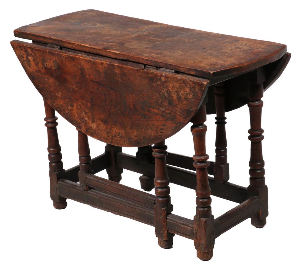 JACOBEAN DROP LEAF SWING LEG TABLE: Early 18th c. Solid Elm Round Table with heavy three-plank top, six sausage and ring turned legs (two are gate legs), resting on bun feet, 25" x 36" x 16" with 11" leaves. Worn, stained, nice age pati