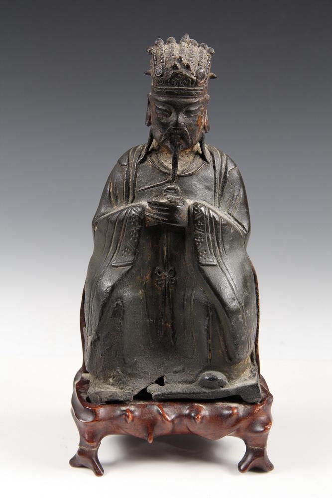 CHINESE BRONZE ALTAR FIGURE: 16th Century Figure of Seated Confucius as a Mandarin, in remnants of gilding, on later custom carved wooden stand, the figure is 7 1/2" (19.1 cm) tall. Cracked and distorted on bottom left edge, loss