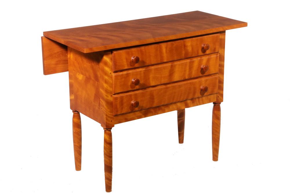 SHAKER TYPE THREE-DRAWER SEWING TABLE: Contemporary Flame Birch Three-Drawer Sewing Table, with drop leaf back, dovetailed construction, wooden drawer pulls, 27" high, 34 1/4" x 16", 7" leaf. Good condition.