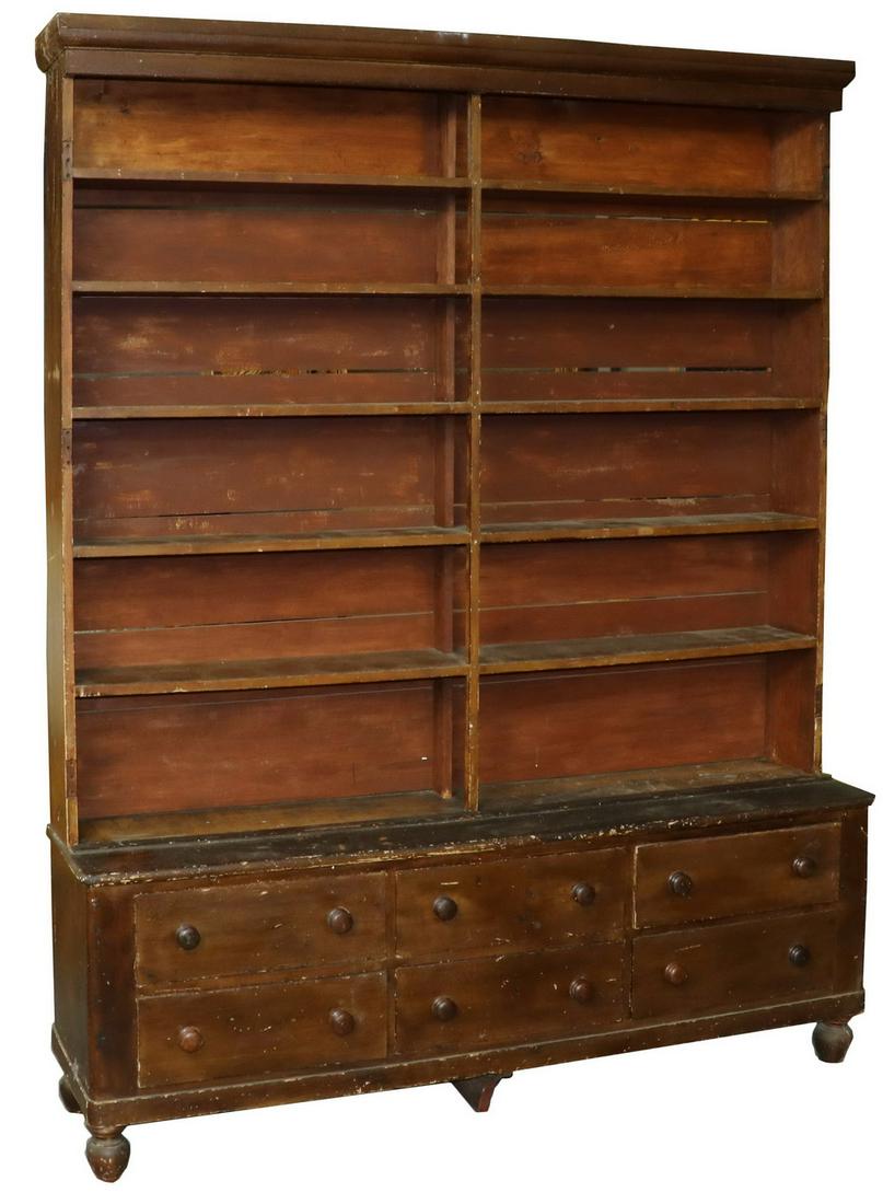 COUNTRY STORE OPEN FRONT STEPBACK CUPBOARD: Pine Cupboard in old brown paint, Maine made, mid 18th c., in two parts, the upper cabinet with molded cornice, six shelves, exposed horizontal backing boards; the lower case holding six drawers with 