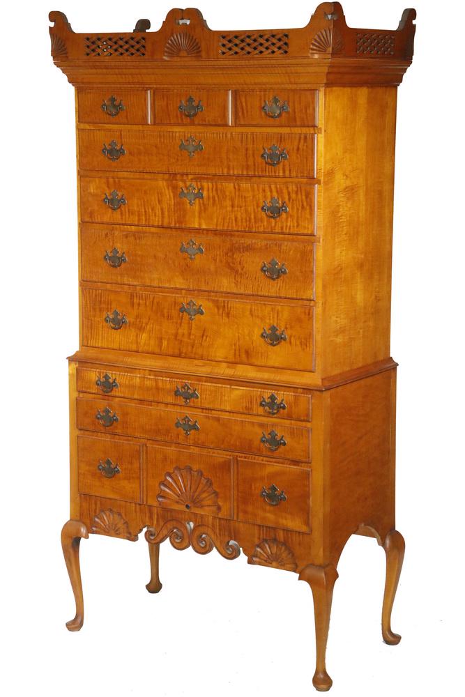 ELDRED WHEELER DUNLAP TIGER MAPLE HIGHBOY: Fine Eldred Wheeler Rampant Tiger Maple Two-Part Dunlap Style Queen Anne Highboy, flat top upper case with molded and basketweave openwork carved overhanging cornice with carved top scrolls and corner