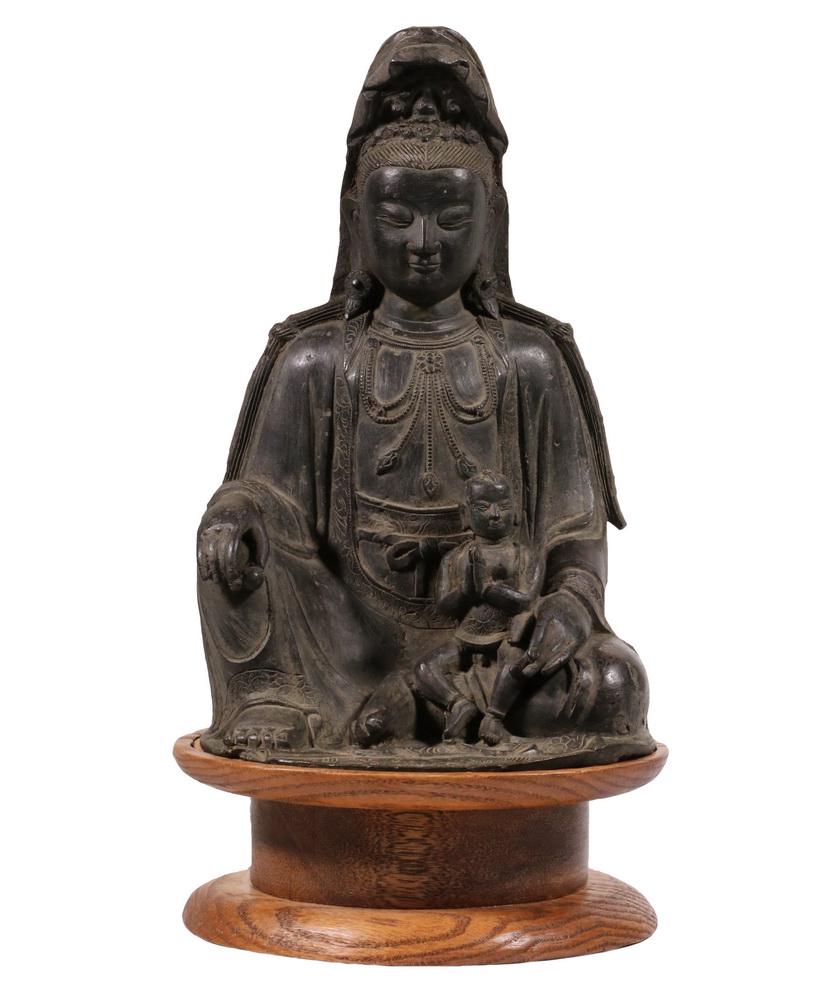 EARLY CHINESE BRONZE: A rare, early depiction of Guanyin, cast bronze, Chinese, the goddess of Mercy shown with the baby Buddha, Ming Dynasty, on oak platform base, 13 1/4" tall (bronze only).
