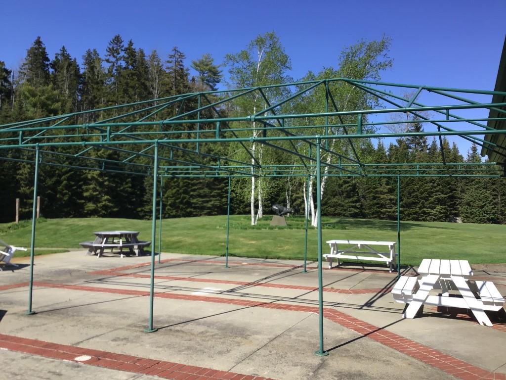 TENT FRAME: Rigid metal pole construction tent frame for exterior canopy, with green canvas cover. 31'6" x 21'3" and 8'8" in height