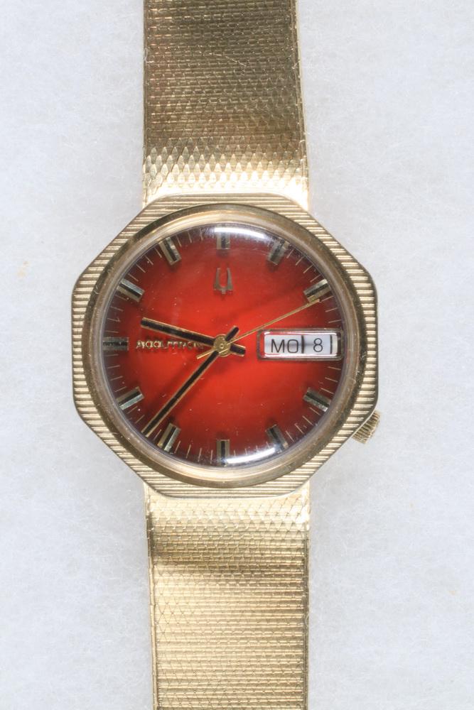 GENT'S 14K GOLD WRISTWATCH: Vintage Bulova N2 Accutron Wristwatch with 14K yellow gold octagon head with garnet dial and day date, has original gold snake skin bracelet, serial #36221. Quartz movement. In original box.