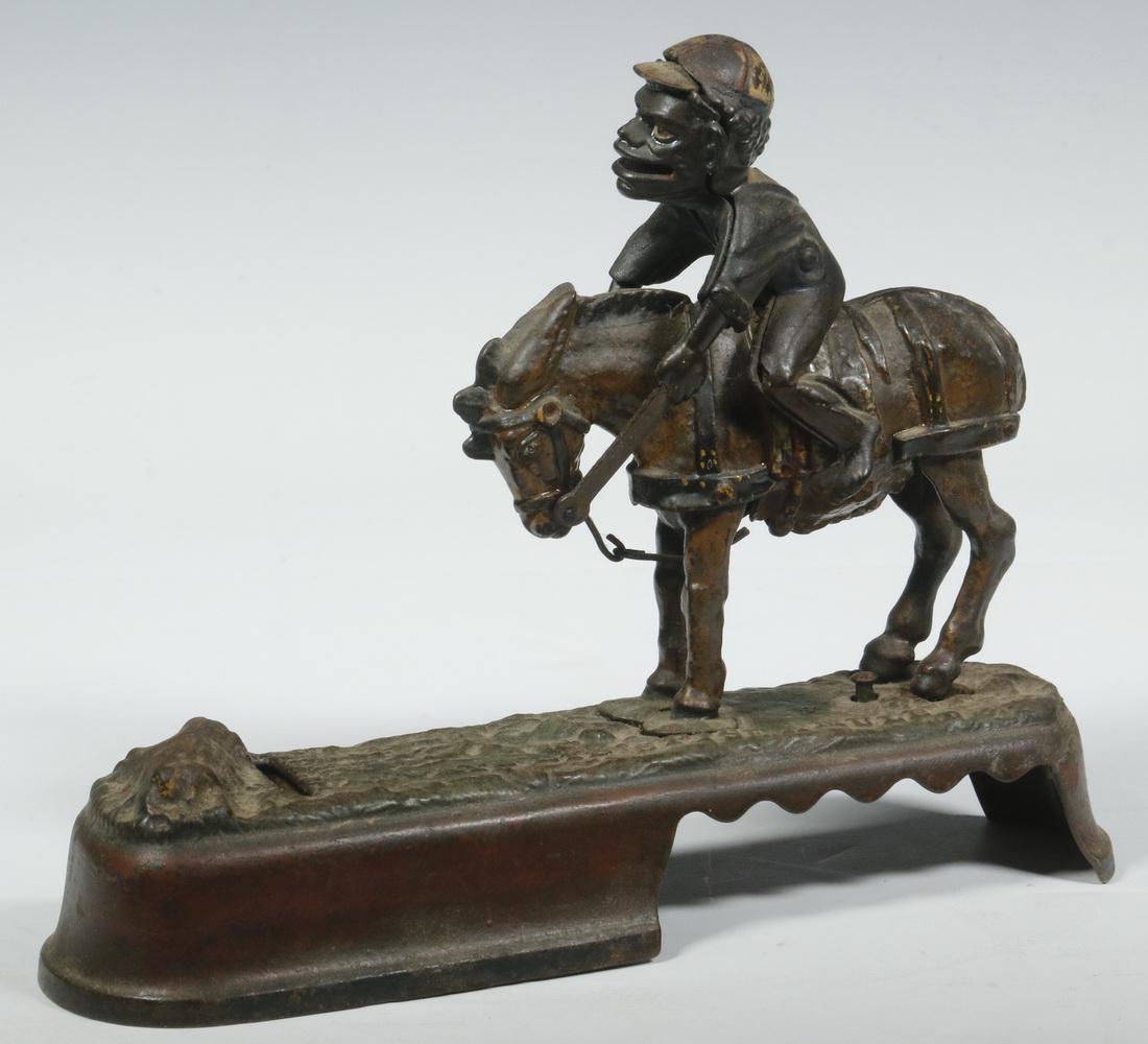 "I ALWAYS DID 'SPISE A MULE" MECHANICAL BANK: Late 19th c. Cast Iron Mechanical Bank by J. & E. Stevens Company, depicting a jockey on bucking horse, a coin placed in the man's mouth goes into the till when a button is pressed that causes the mul