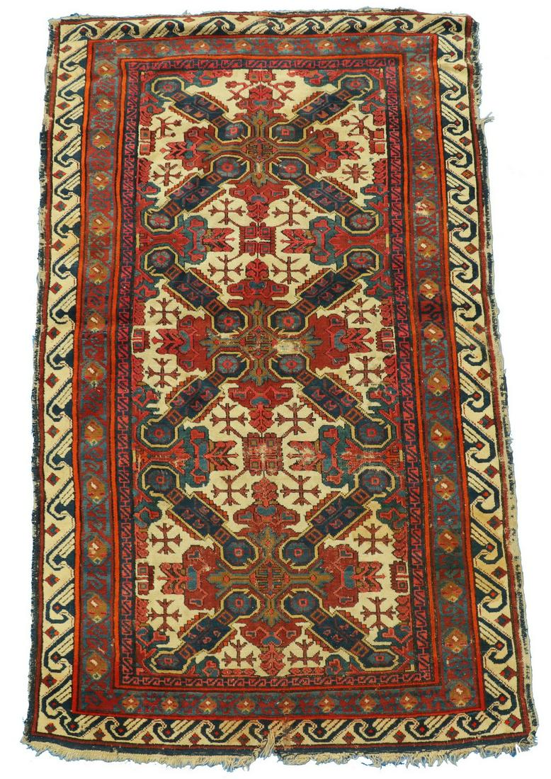 SEICHOUR RUG - 3'-10" x 6'-6": Northeast Caucasus, three 'St. Andrews' cross motifs in midnight blue, sky blue, maroon and blue-green on the ivory field, ivory latch hook and diamond border. Selvage damage, repairs, tear at one end