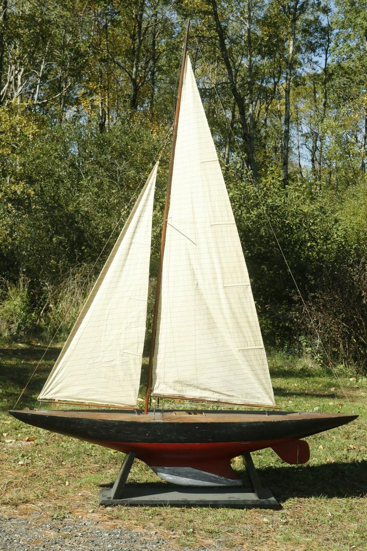LARGE RED AND BLACK PAINTED HULL POND MODEL: Plank built wooden hull, weighted deep racing keel, circa 1900, with original mast and cotton sails, on display stand, 80" (6'-8") long, 87" (7'-3") mast. Good condition, minor rigging tears. Provenan