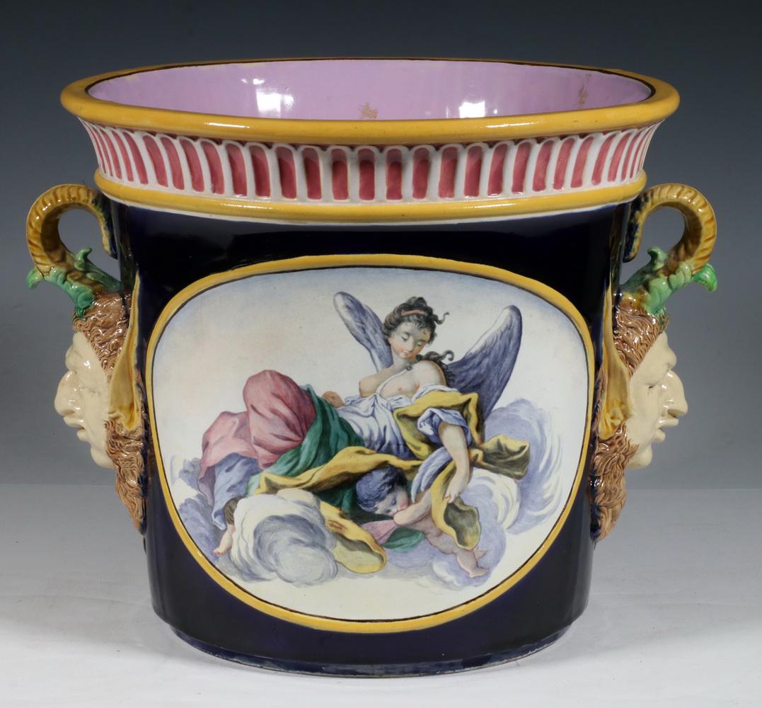 MAJOLICA JARDINIERE WITH SATYR HEAD HANDLES: Late 19th c. Large Majolica Pottery Planter, in the manner of Minton, with painted figural panels and applied side handles in the form of satyr heads, pink glazed interior, multicolor glazed base with