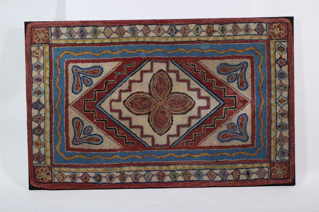 STRETCHED GEOMETRIC HOOKED RUG - 43 1/2" x 27 1/2": Pale blue, pink and white, with central four leaf clover, blossom brackets, lappet band, on black mount. Very good condition. Provenance: From the estate of Richard Suydam, Ellsworth, ME.