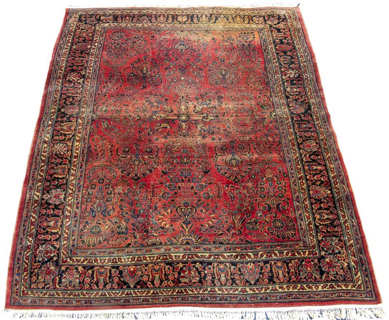 SAROUK CARPET: Overall design of floral sprays, flowering vines, rosettes and palmettes in midnight and royal blue, gold and red on the rust red field, midnight blue serrated leaf and palmette border, 9'-6" x 11'-9"