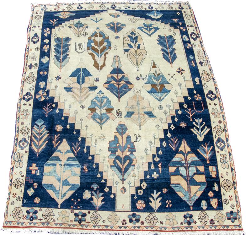 USHAK CARPET: A tan-ivory field filled with large geometric and plant motifs in gold, sky and navy blue and rust, midnight blue spandrels, tan-ivory rosette border, 8' x 10'-6". Even wear.