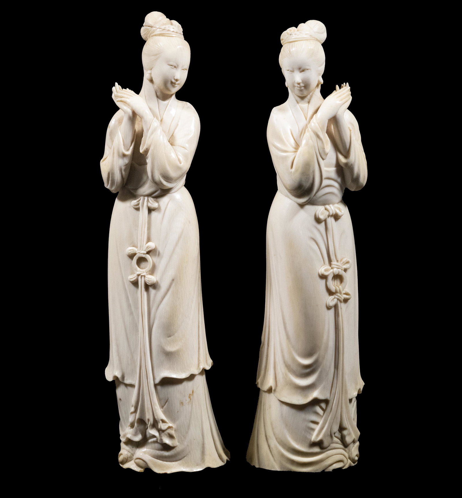 A 19TH C. PR OF SIGNED CHINESE FIGURINES: A Pair of Qing Dynasty Beauties, standing in mirrored poses, with hands clasped up to one shoulder, well carved with coiffed hair, finely detailed robes, 9 3/4" tall. Separation to one hair bun, yello