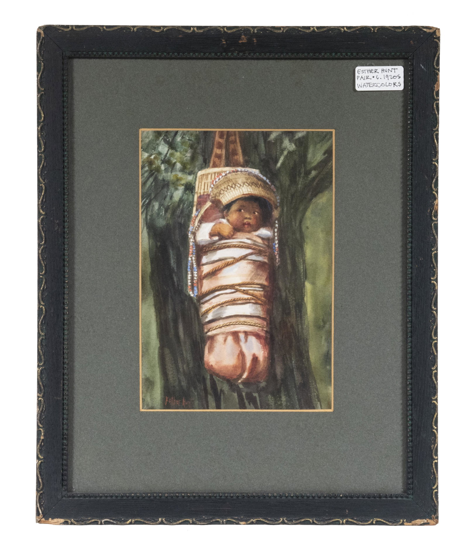 ESTHER ANNA HUNT (CA/NE, 1875-1951): Female Papoose, watercolor on paper, signed lower left, circa 1920, depicted in pink blanket with covered head, hanging against a tree, looking at the viewer, housed in black molded frame with gilt ed