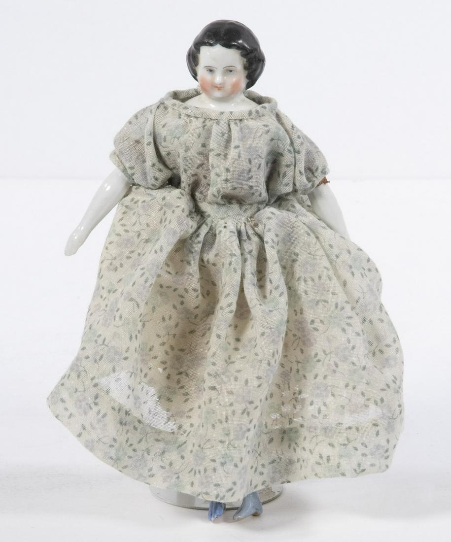 JENNY LIND CHINA HEAD MINI-DOLL: Small Jenny Lind Design Doll, with china head, arms and legs, cloth body, in a Victorian style dress and petticoat, 6 1/2" high. Minor paint loss.