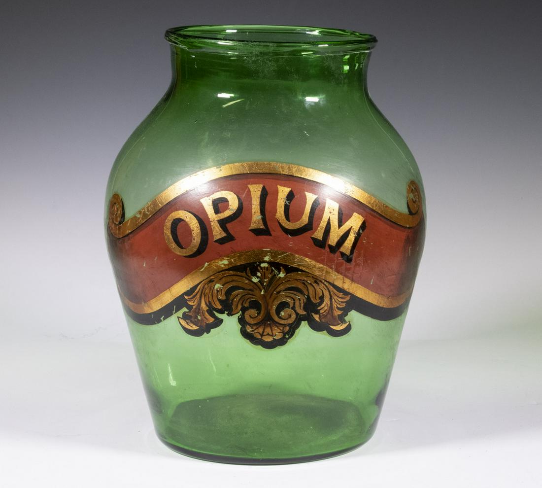 LARGE GREEN GLASS MEDICAL BOTTLE "OPIUM": Pale Green Hipped Jar, mold blown, with wine colored enamel paint and gilt ornate label, 13" x 9 1/2", some loss to label.