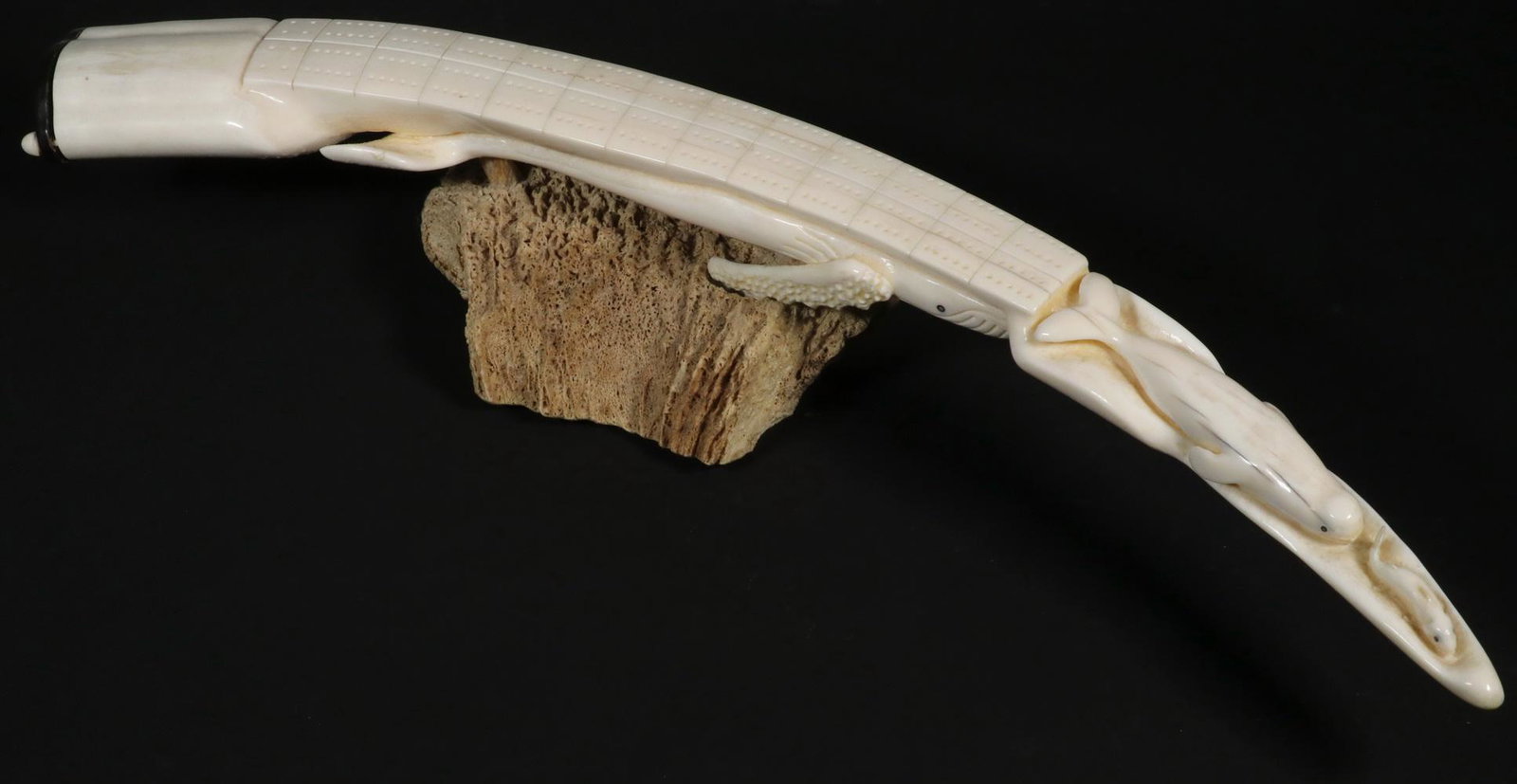 YU'PIK ESKIMO CRIBBAGE BOARD FROM WALRUS TUSK BY JOHN EDGAR HANSON, JR. (1955-2012) OF EMMONAK,: Carved from a single tusk, mounted on the crown of a Musk Ox skull. Signed and dated July 30, 1992 on underside, peg storage at end, 22 1/2" long. Good condition. Provenance: From the Collection of Wi