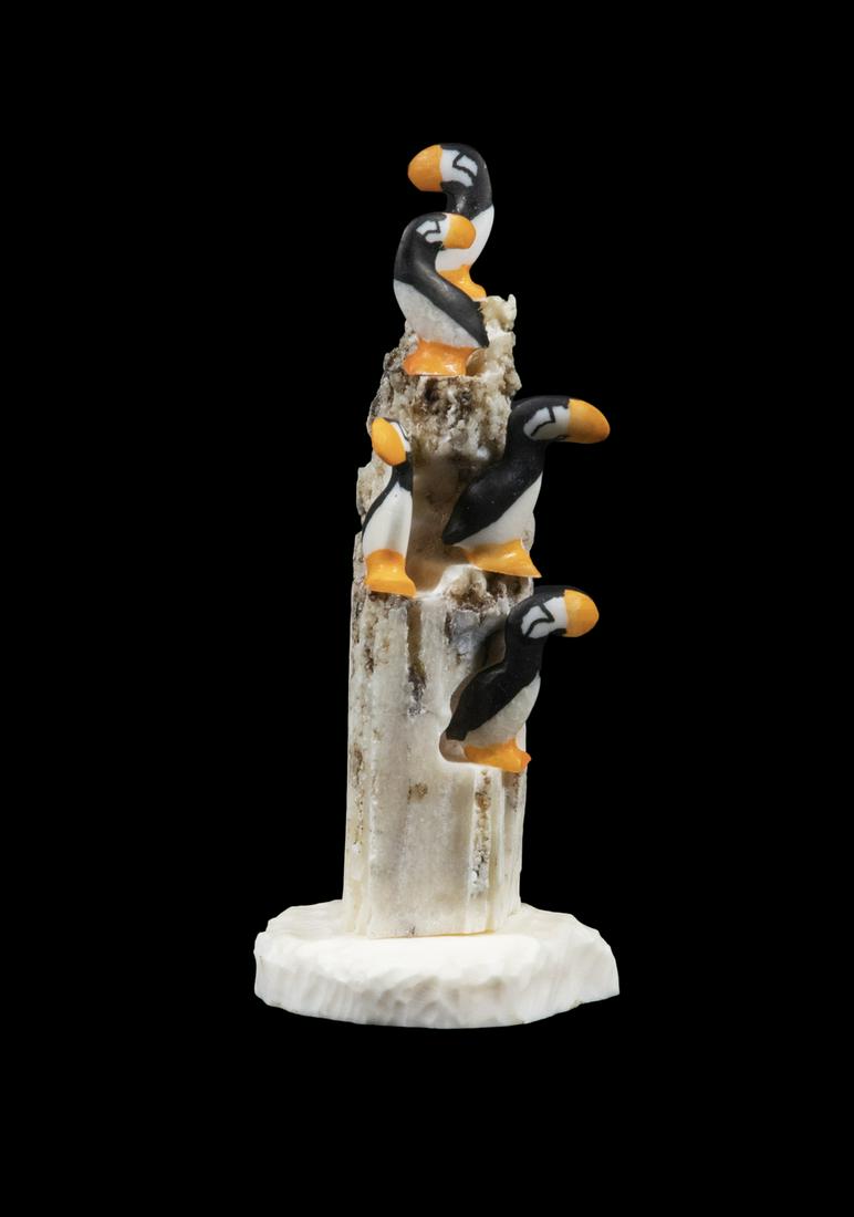 INUIT SCULPTURE OF A PUFFIN ROOKERY BY JUSTIN TIULANA: Inupiac, King Island, Alaska, Carved and painted ivory figures mounted on walrus bone rock formation on ivory plateau, signed on the underside and marked "KI KRAZ", circa 2990, 4 1/2" tall. Good condi