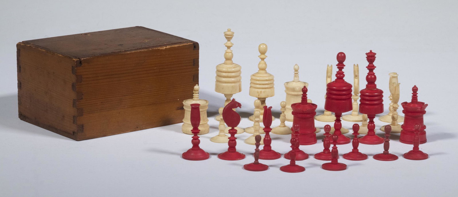 BARLEYCORN BONE CHESS SET: 19th c. (32) Piece Barleycorn Type Natural and Red Stained Carved Bone Set, 1" to 3" high, extra natural base piece and one extra red tip; one red and one natural pawn loose from base; in a dovetailed