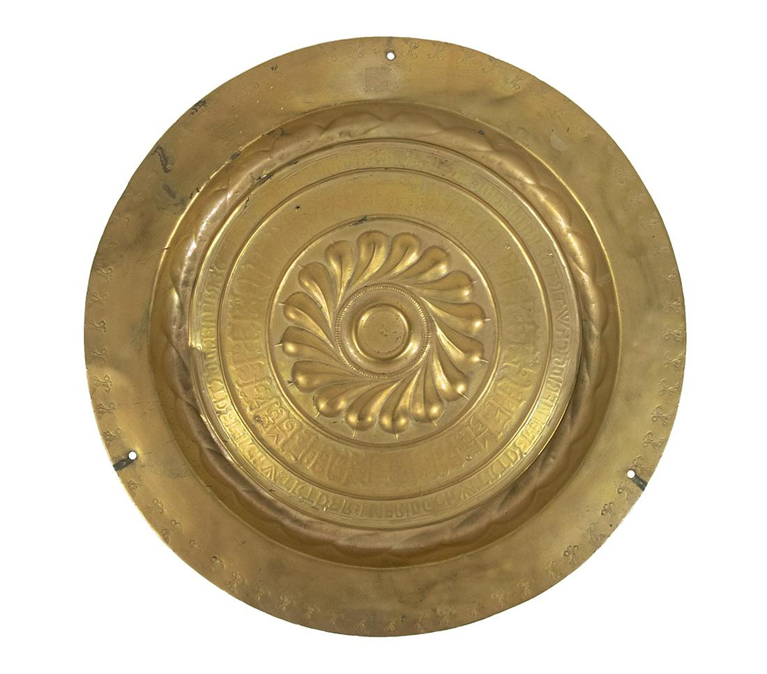 GERMAN BRASS ALMS DISH: 16th c. Nuremburg Brass Alms Basin, with raised petal form central boss, two surrounding rings of Gothic inscription, and punch decorated border, 17 1/4" diam. Three drilled holes to outer rim, surfac