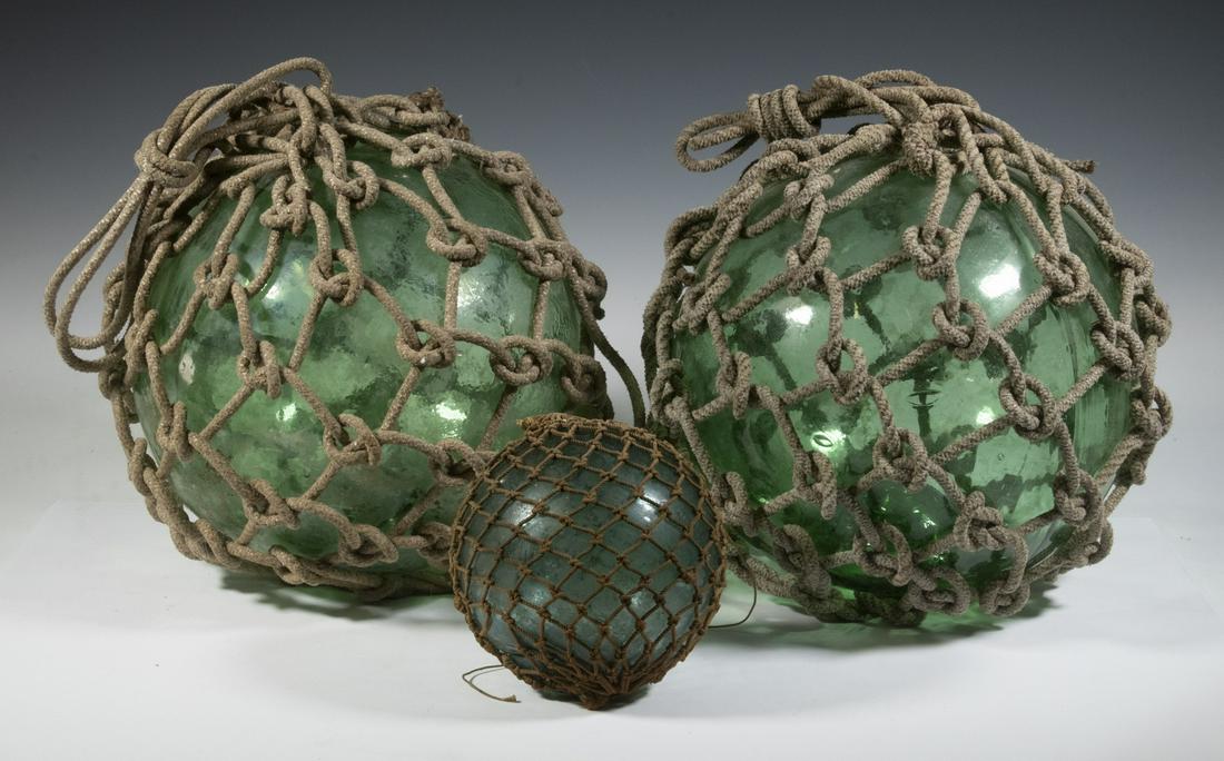 JAPANESE GLASS FISHING FLOATS: Lot of (3), in blown green glass, with ropes, incl: (2) Large size, with pushed in polished base, 11" diam.; and (1) Small, 6" diam.