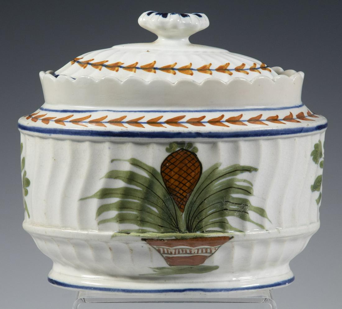 PEARLWARE PINEAPPLE SUGAR BOWL: Early 19th c. English Oval Lidded Bowl, with fluted body and scalloped rim, painted pineapple decoration, 5 1/4" high, 6" x 4 1/2". Professionally restored chips.