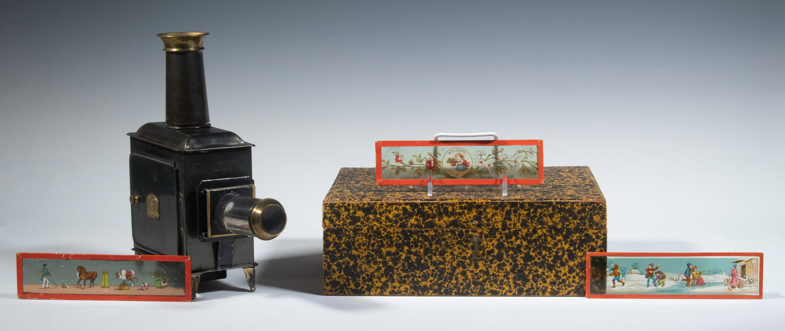 CHILD'S MAGIC LANTERN WITH SLIDES IN THE ORIGINAL BOX: German manufacture, maker's mark EP, with instructions in German, French and English on a lebel under the lid, the box in paper tortoiseshell with colorful label, the lantern in black and gold tin, re