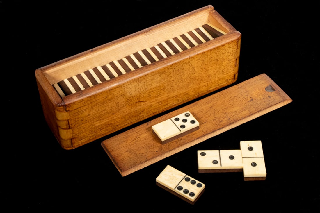EARLY BOXED DOMINOES: 19th c. Partial Set of (24) Dominoes, in a slide top mahogany box with exposed dovetailed construction, ivory topped wooden dominoes, box: 2 1/2" high, 8" x 2 1/4". Good condition.