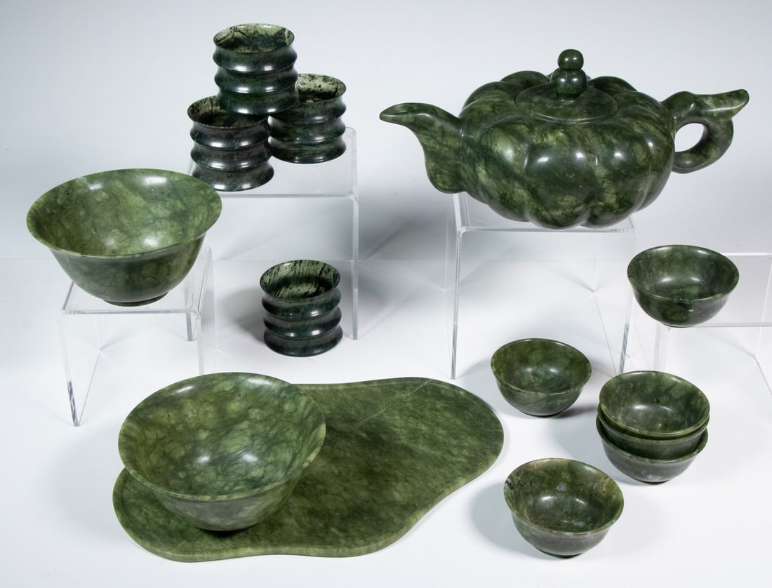 CHINESE SPINACH JADE TEA SERVICE: (14) Piece Carved Jade Lot, incl: Lobed teapot, 4" high, 8 1/4" wide; Quadrilobe shape stand, 8 1/2" x 6"; (6) Teacups, 1" high, 2 1/4" diam.; (2) Bowls, 2" high, 4" diam.; and Set of (4) channeled cu