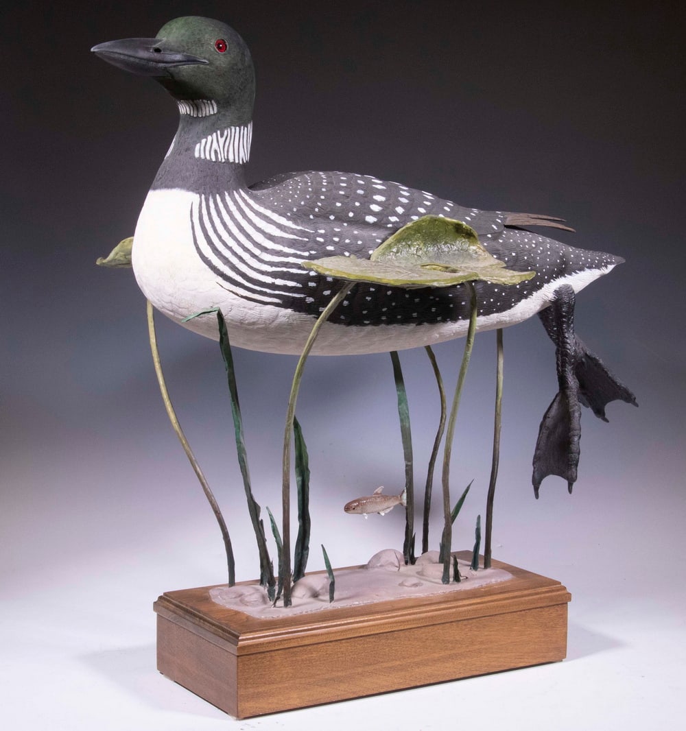 ROBERT MELBURN DOUCETTE (ME, 1930-2023): Swimming Loon, carved and painted wooden sculpture, signed on top of base, an aquatic scene with a water bird figure suspended amid aquatic plants and fish, with glass eyes, composition and metal plan