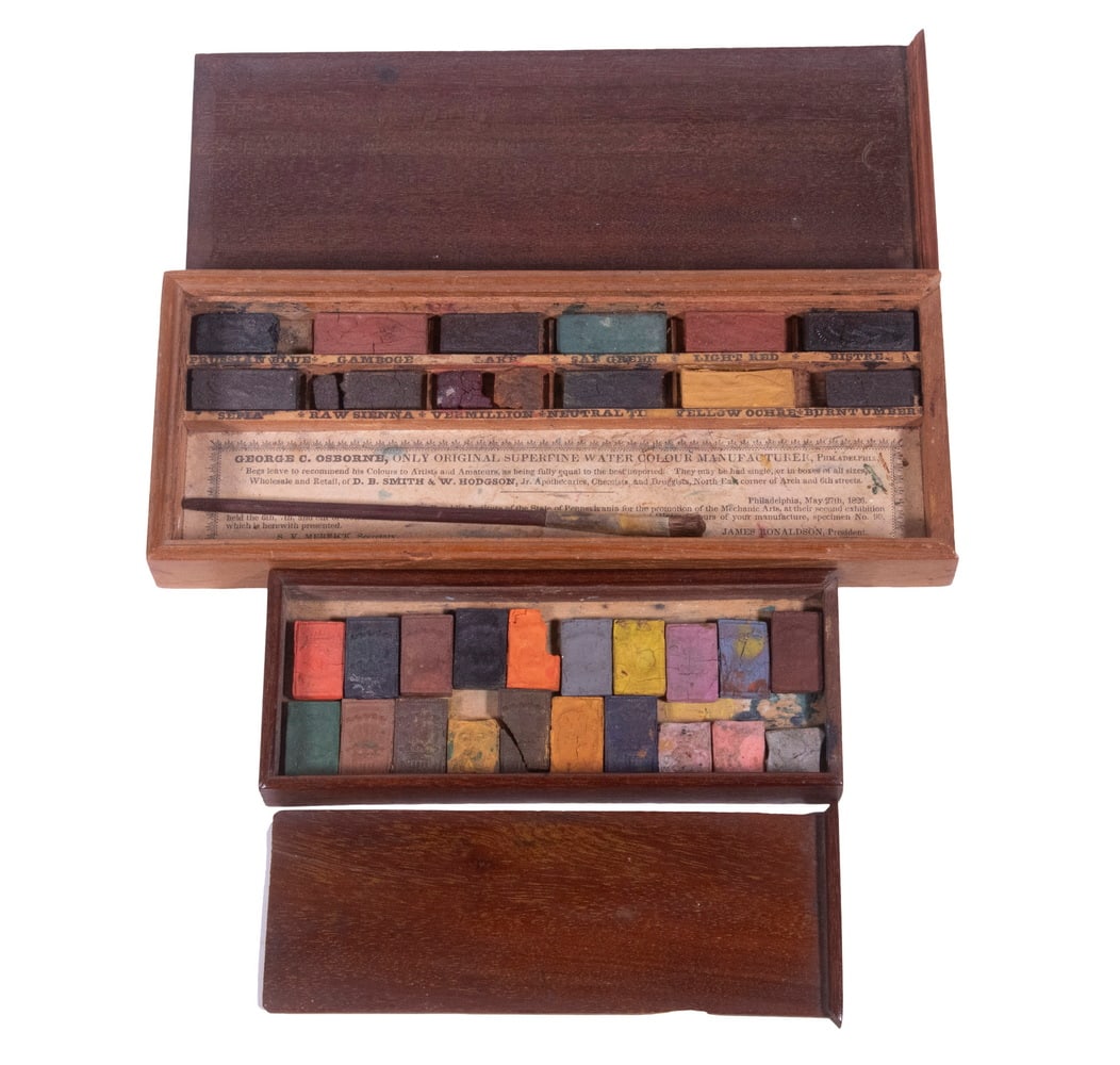 (2) 19TH C. BRITISH BOXES OF CAKE WATERCOLORS, USED: Both in mahogany with sliding lids, the larger ca. 1830, having twelve cakes and a miniature brush and paper label from George S. Osborne, northeast corner of Arch and 6th Streets, Philadelphia, 3/4" 
