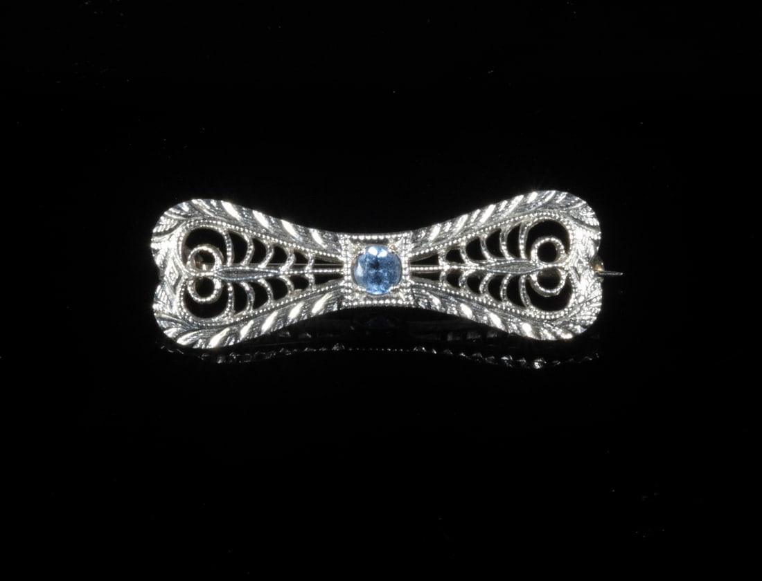 GOLD BOW PIN WITH AQUAMARINE: Small 14K White Gold Bow Form Pin, filigree design center set with a small faceted stone, 1" wide, 0.7 dwt tw.